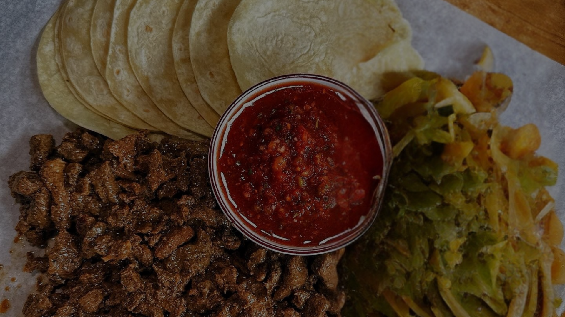 Assorted Mexican food items including tortillas, salsa, and ground meat on a paper plate.