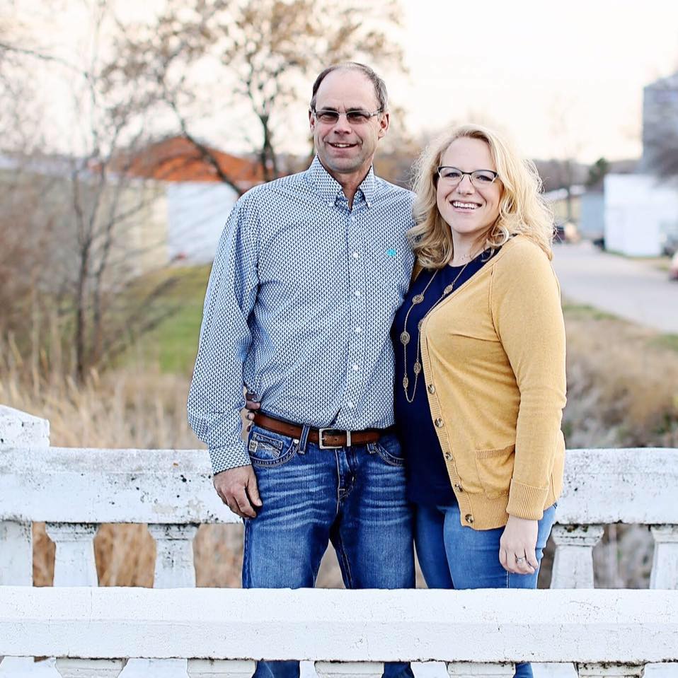 Man and woman standing together on a wooden bridge with a blurred background