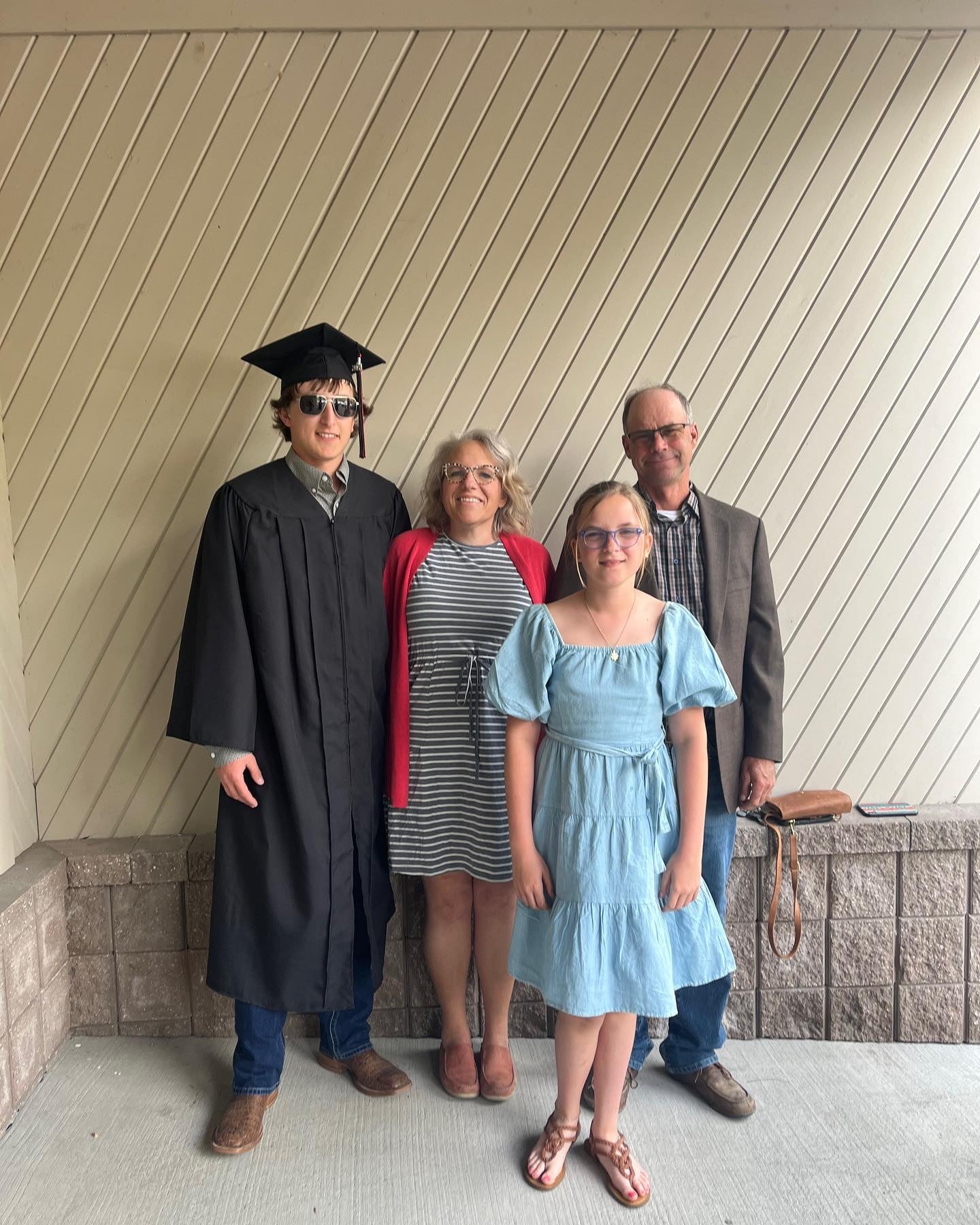 Graduate in cap and gown with family on a porch